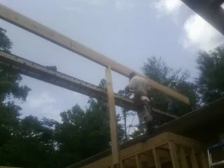 Carpenter setting a ridge beam over a new addition frame — Ice Dam Removal by Roofing Brothers in Nedrow