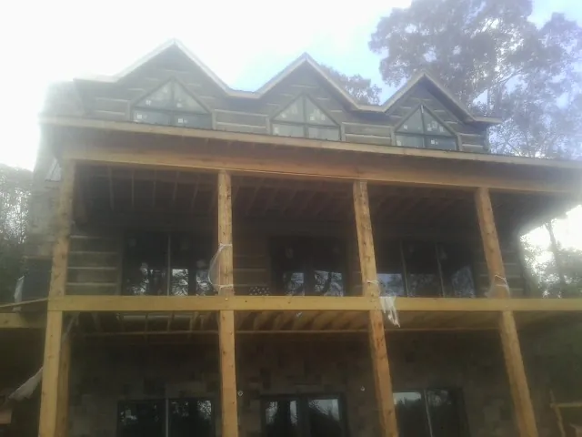 Dormers and porch framing on a large log home under construction — Roof Coating work by our crew in Nedrow