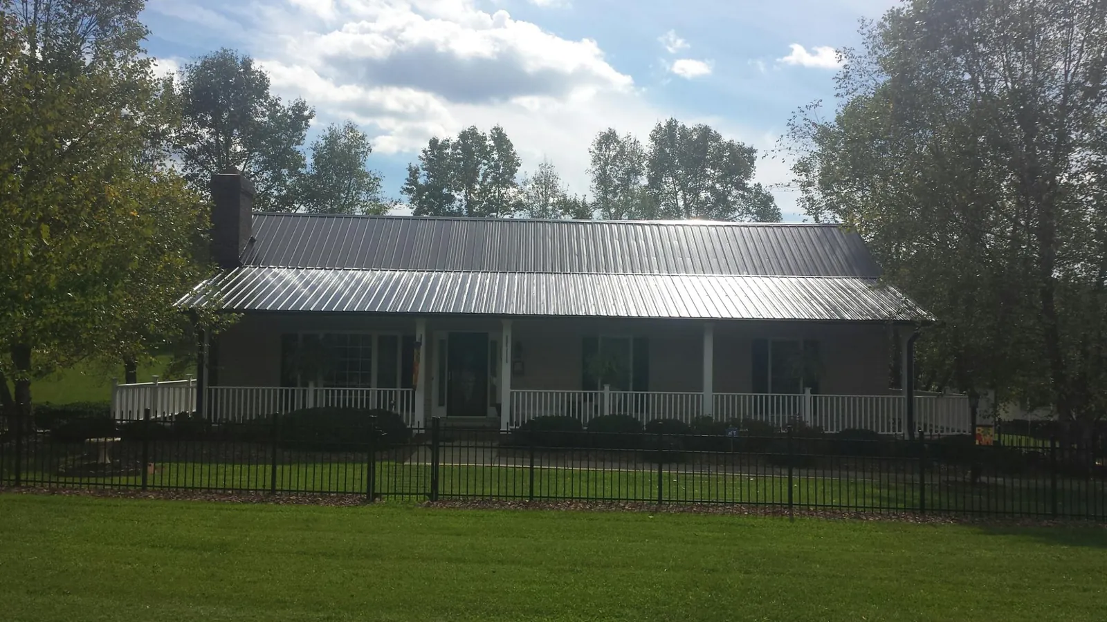 Gray metal roof on a brick ranch with a full width front porch — Gutter Guard Installation work by our crew in Nedrow