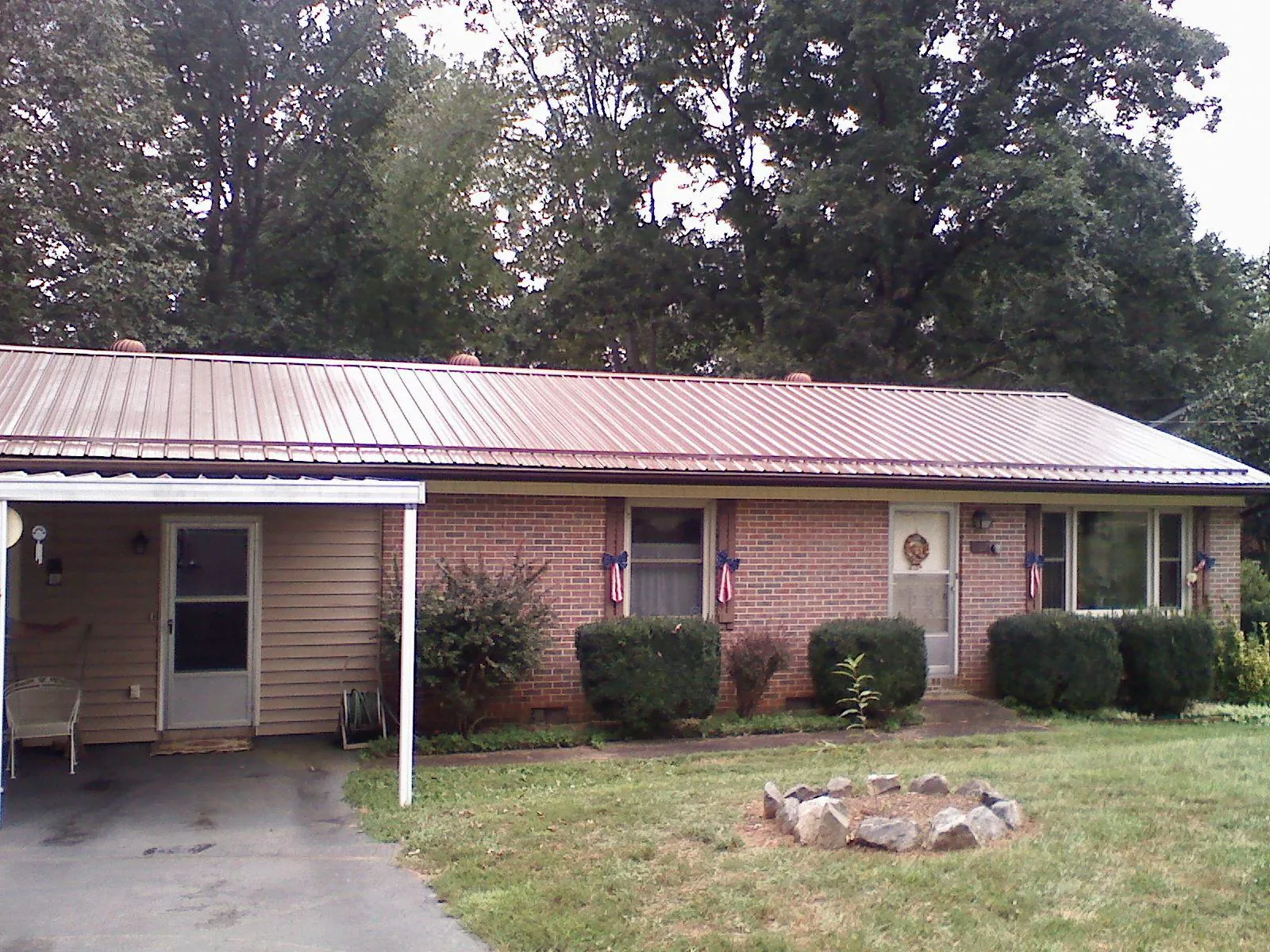 Bronze metal roof and carport on a brick ranch home — Roof Repair work by our crew in Nedrow